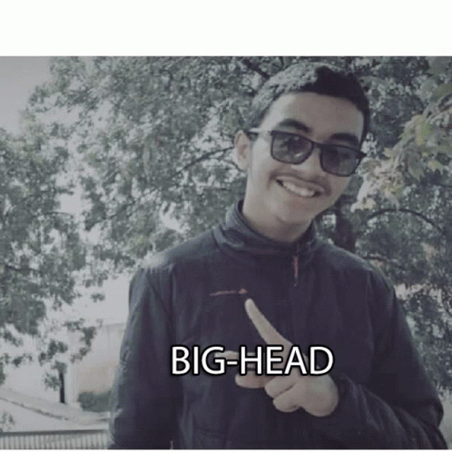 A Young Man Wearing Sunglasses And A Black Jacket Is Pointing At The Camera With The Words Big-Head Written Below Him GIF