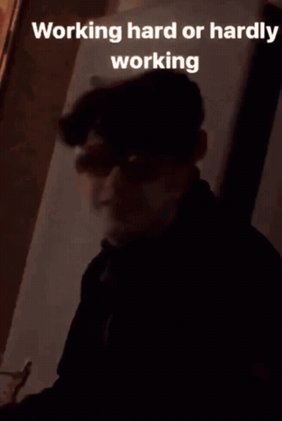 A Young Man Wearing Sunglasses And A Black Jacket Is Sitting In Front Of A Wall . GIF