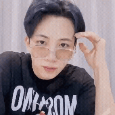 A Young Man Wearing Sunglasses And A Black T-Shirt Is Adjusting His Glasses . GIF