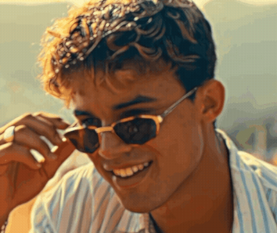 A Young Man Wearing Sunglasses Is Smiling For The Camera GIF