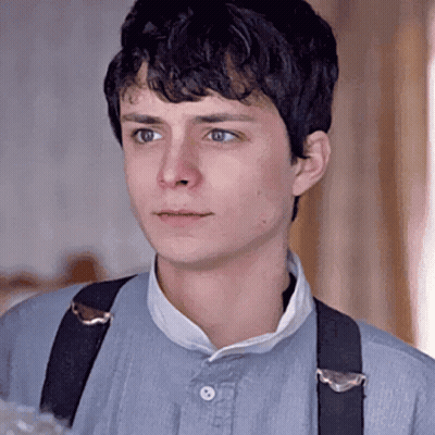 A Young Man Wearing Suspenders Is Looking At The Camera . GIF