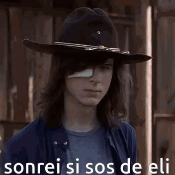 A Young Man With A Bandage On His Eye Is Wearing A Cowboy Hat And A Blue Shirt . GIF