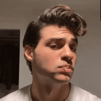 A Young Man With A Cigarette In His Mouth Looks At The Camera GIF