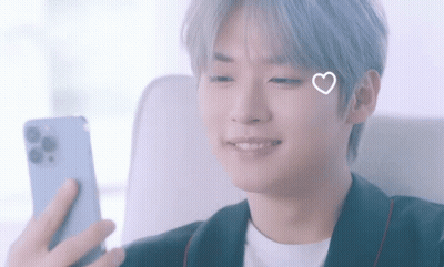 A Young Man With A Heart On His Face Is Looking At His Phone GIF