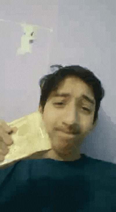 A Young Man With A Mustache Is Holding A Piece Of Paper In His Hand . GIF