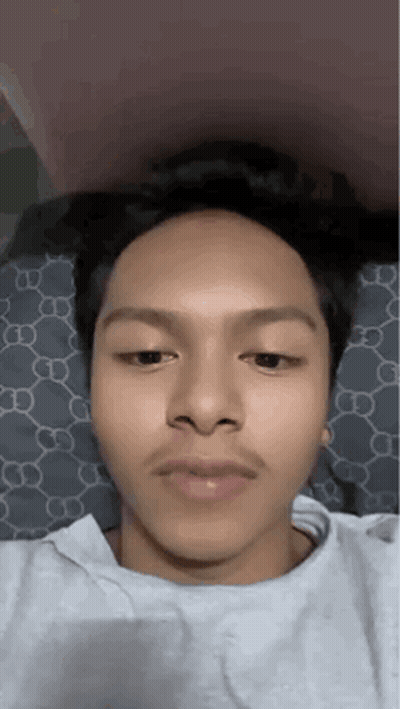 A Young Man With A Mustache Is Laying On A Bed And Making A Funny Face . GIF