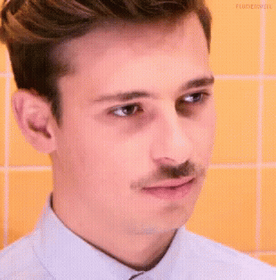 A Young Man With A Mustache Is Making A Funny Face . GIF