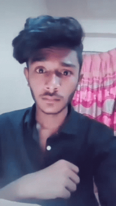 A Young Man With A Mustache Is Making A Funny Face While Wearing A Black Shirt . GIF