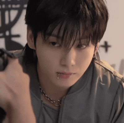 A Young Man With A Piercing In His Lip Is Holding A Camera . GIF