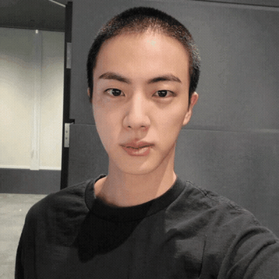 A Young Man With A Shaved Head Looks At The Camera GIF