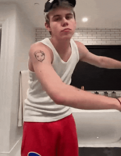 A Young Man With A Tattoo On His Arm Wearing Red Shorts GIF