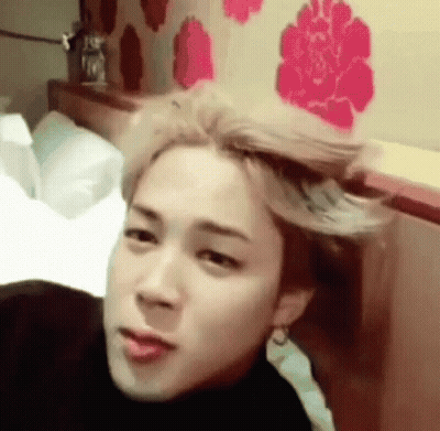 A Young Man With Blonde Hair Is Laying On A Bed With His Hair Blowing In The Wind . GIF