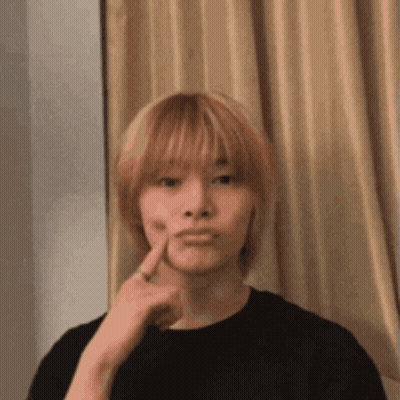 A Young Man With Blonde Hair Is Making A Funny Face While Holding His Finger To His Face . GIF