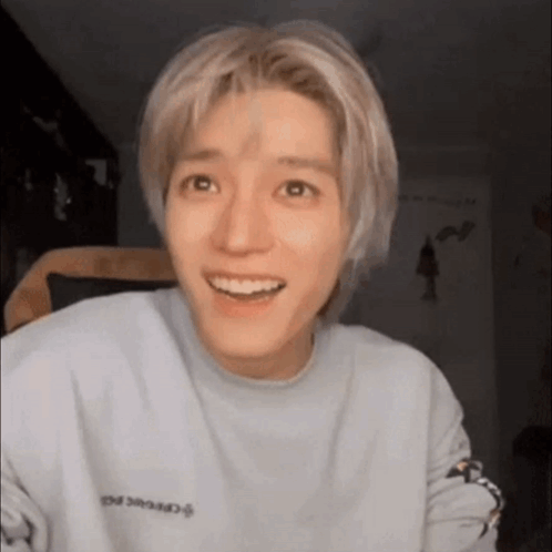 A Young Man With Blonde Hair Is Smiling And Wearing A Blue Sweatshirt . GIF