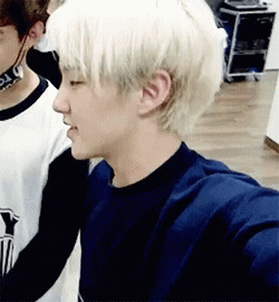 A Young Man With Blonde Hair Is Standing Next To Another Young Man In A Room . GIF