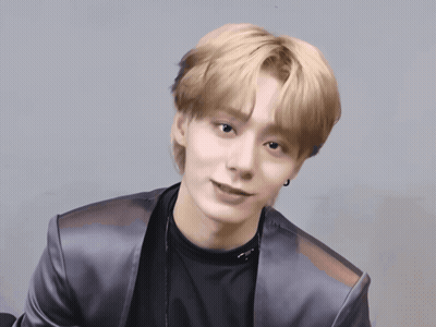 A Young Man With Blonde Hair Is Wearing A Black Shirt And Silver Jacket GIF