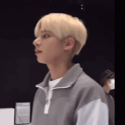 A Young Man With Blonde Hair Is Wearing A Gray Jacket . GIF