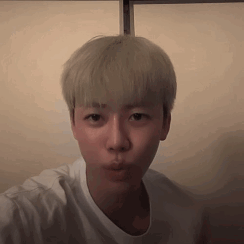 A Young Man With Blonde Hair Is Wearing A White Shirt And Making A Face . GIF