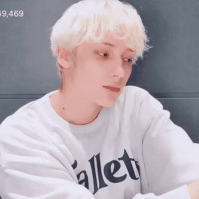 A Young Man With Blonde Hair Is Wearing A White Sweatshirt With The Word Ballet On It . GIF