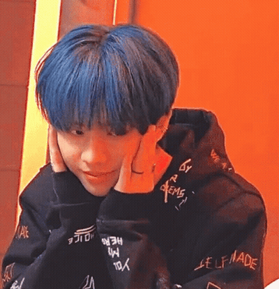 A Young Man With Blue Hair Is Wearing A Black Hoodie And A Ring On His Finger . GIF