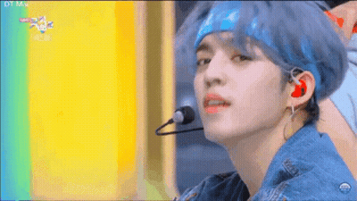 A Young Man With Blue Hair Is Wearing A Headband And Earphones While Singing Into A Microphone . GIF