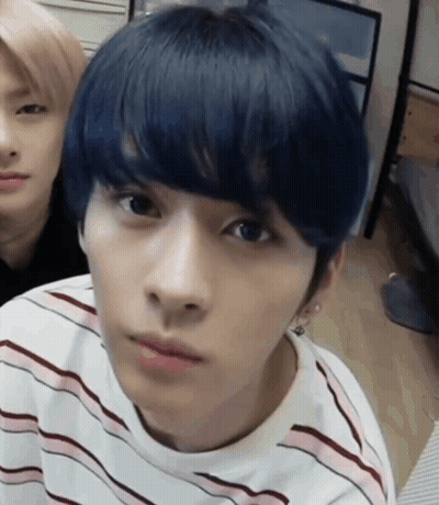A Young Man With Blue Hair Is Wearing A Striped Shirt And Looking At The Camera . GIF