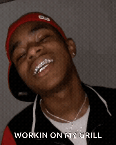 A Young Man With Braces On His Teeth Is Smiling With His Eyes Closed And Says `` Workin On My Grill '' . GIF