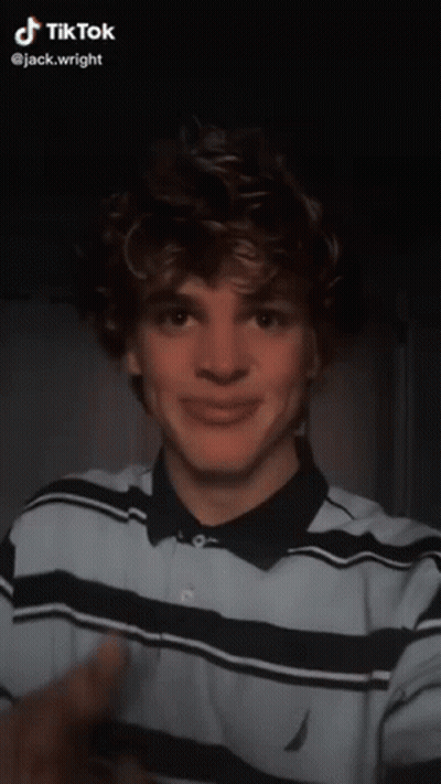 A Young Man With Braces On His Teeth Is Wearing A Blue And Black Striped Shirt And A Ring On His Finger GIF