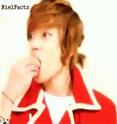 A Young Man With Brown Hair Is Wearing A Red Jacket And Eating Something . GIF