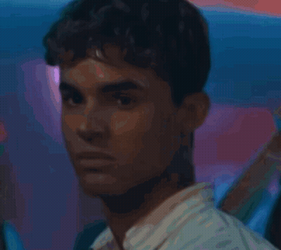 A Young Man With Curly Hair Is Holding A Glass Of Water GIF
