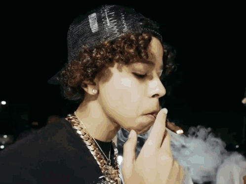 A Young Man With Curly Hair Is Smoking A Cigarette And Wearing A Hat That Says ' Supreme ' On It GIF