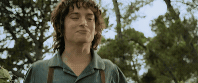 A Young Man With Curly Hair Is Standing In Front Of Trees GIF