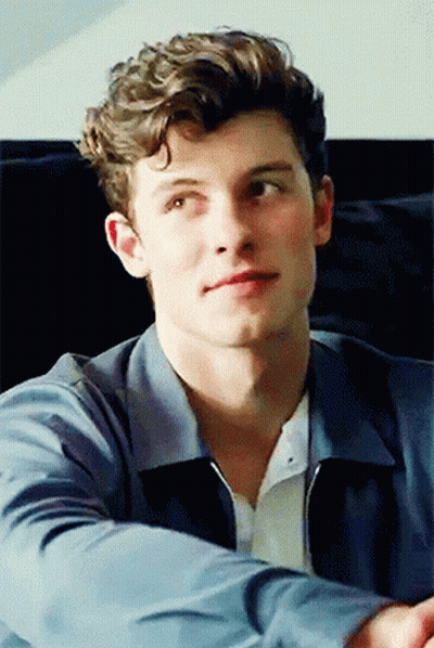 A Young Man With Curly Hair Is Wearing A Blue Jacket And A White Shirt GIF