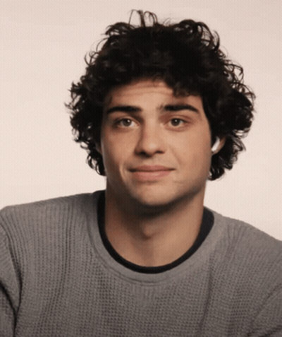 A Young Man With Curly Hair Is Wearing A Gray Sweater GIF
