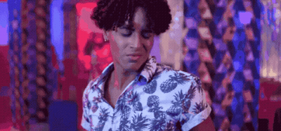 A Young Man With Curly Hair Is Wearing A Pineapple Shirt And Dancing In A Club . GIF