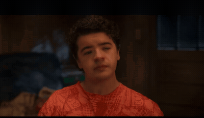 A Young Man With Curly Hair Is Wearing A Red Shirt With A Pattern Of Letters GIF