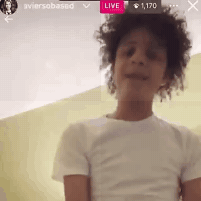 A Young Man With Curly Hair Is Wearing A White T-Shirt And Talking On A Video Call . GIF