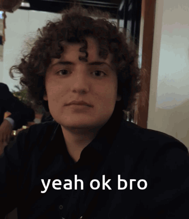 A Young Man With Curly Hair Says " Yeah Ok Bro " In White Letters GIF