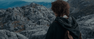 A Young Man With Curly Hair Stands In Front Of A Mountain GIF