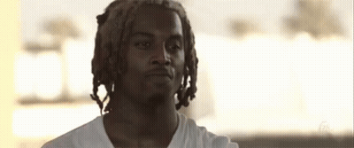 A Young Man With Dreadlocks And A Beard Is Wearing A White Shirt GIF