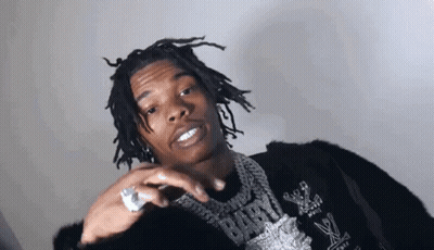 A Young Man With Dreadlocks And A Ring On His Finger Is Wearing A Black Jacket And A Necklace . GIF