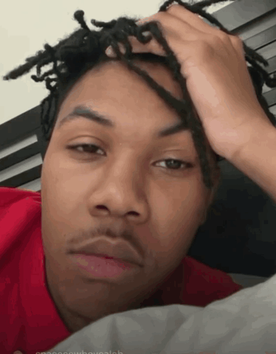 A Young Man With Dreadlocks Is Laying On A Bed GIF