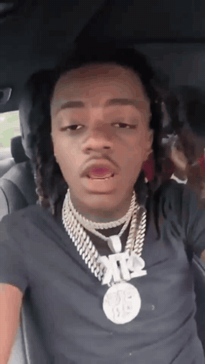 A Young Man With Dreadlocks Is Sitting In The Back Seat Of A Car . GIF