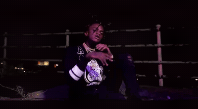A Young Man With Dreadlocks Is Smoking A Cigarette In A Dark Room . GIF