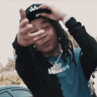 A Young Man With Dreadlocks Is Wearing A Hat And Making A Peace Sign GIF