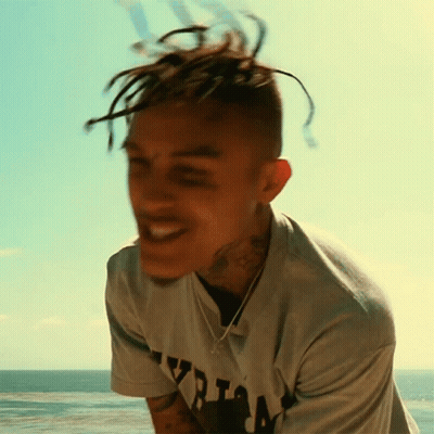 A Young Man With Dreadlocks Is Wearing A Shirt That Says ' Yzria ' On It GIF