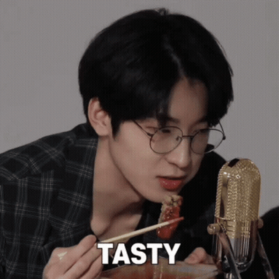 A Young Man With Glasses Is Eating Food With Chopsticks And The Word Tasty Is On The Bottom GIF