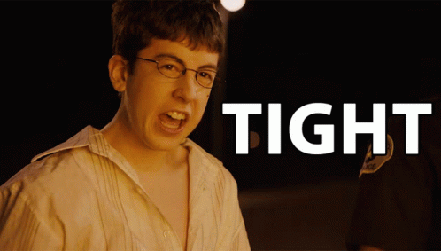 A Young Man With Glasses Is Screaming In Front Of A Sign That Says Tight GIF