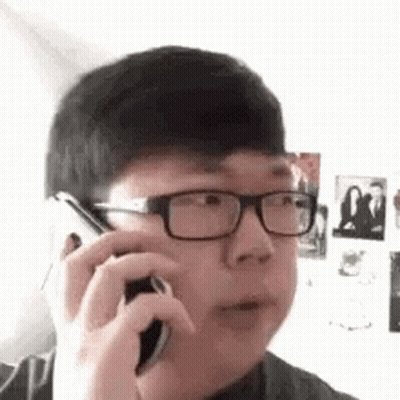 A Young Man With Glasses Is Talking On A Cell Phone . GIF