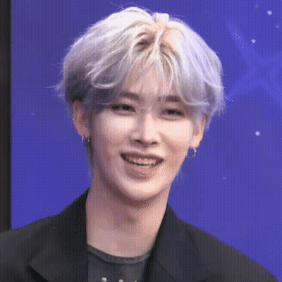 A Young Man With Gray Hair Is Smiling And Wearing A Black Jacket And Earrings . GIF